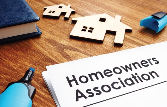 homeowners association annual mailing packet on the homeowner association managers desk with HOA homes around it.