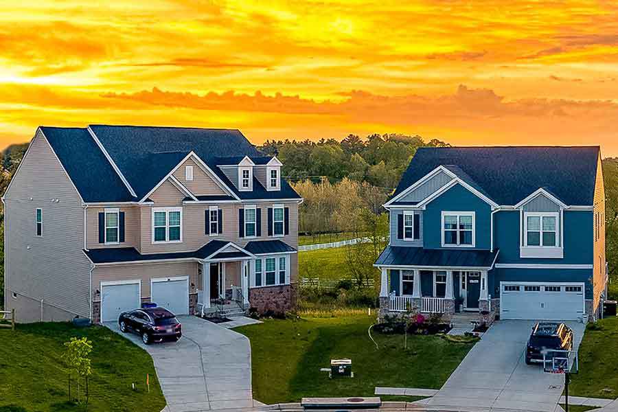 Two HOA homes next door to each other showcasing a homeowners association community with a sunset in the background.