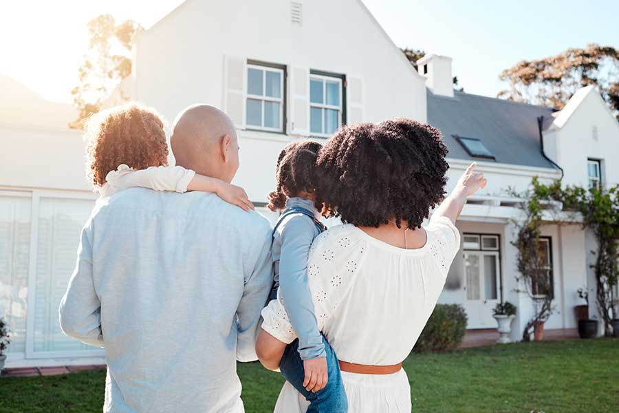 A family standing in front of a house in an HOA community pointing to their house.