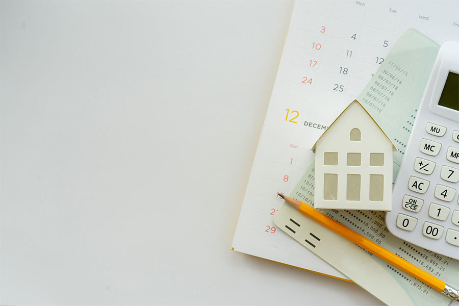 A small house next to a calculator with a pencil and a property management statement and calendar on the bottom representing tenant fees.