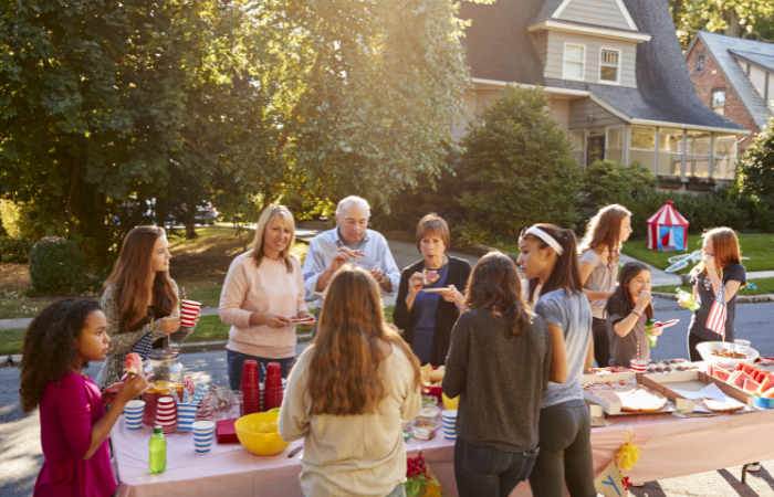 A self-managed HOA community gathering with community members and families having a BBQ in front of the houses.